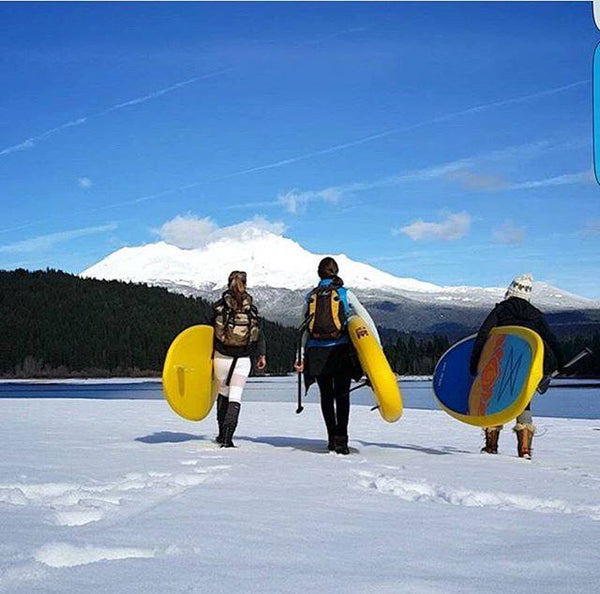women carrying paddle boards