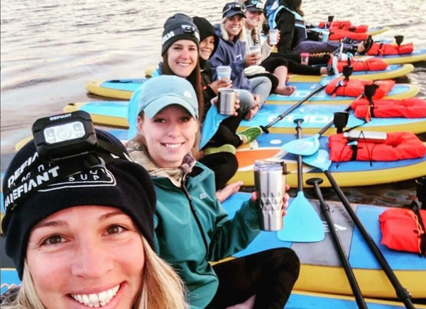 women sitting on paddle boards